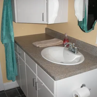 Bathroom vanity with a gray countertop, white cabinet, and sink