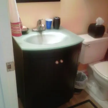 Compact bathroom with a dark vanity, white sink, and toilet