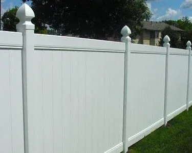 White vinyl privacy fence with pointed posts beside a grassy yard