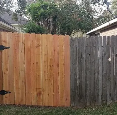New cedar fence gate joined to a weathered wooden fence