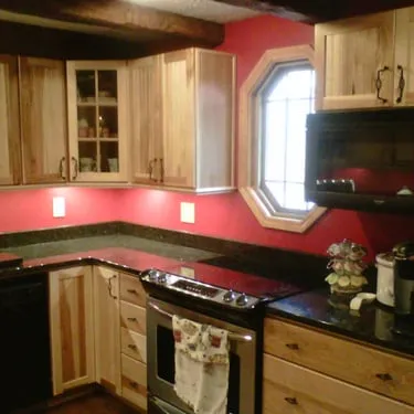 Kitchen with natural wood cabinets, red walls, and dark countertops