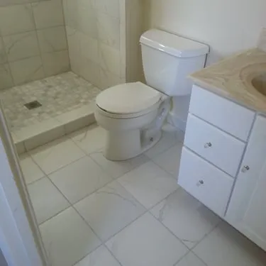 Bathroom with white vanity, tiled floor, shower, and toilet