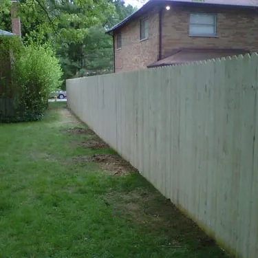 Long pale wooden privacy fence beside a grassy yard