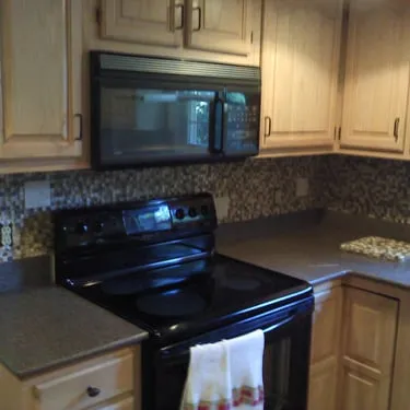 Kitchen with wood cabinets, a microwave, stove, and tiled backsplash